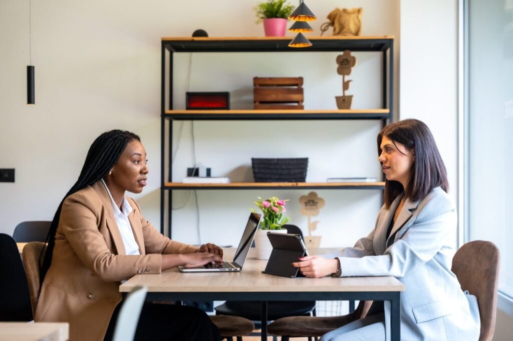 two women sitting across from a desk having a serious conversation