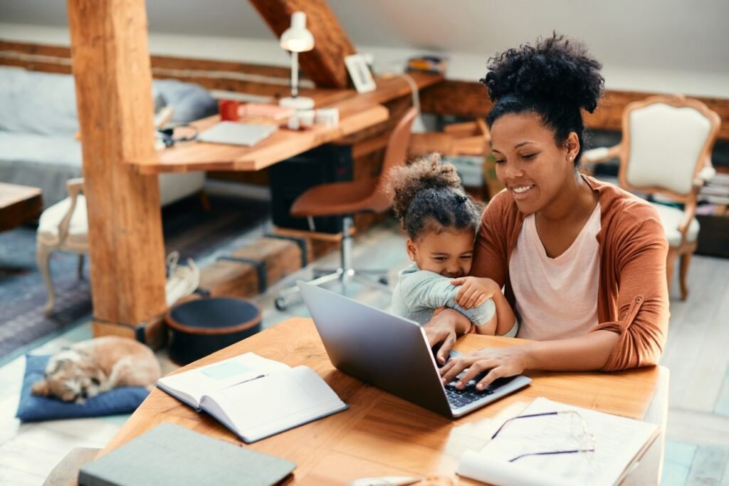women at desk working while small child hugs her arm